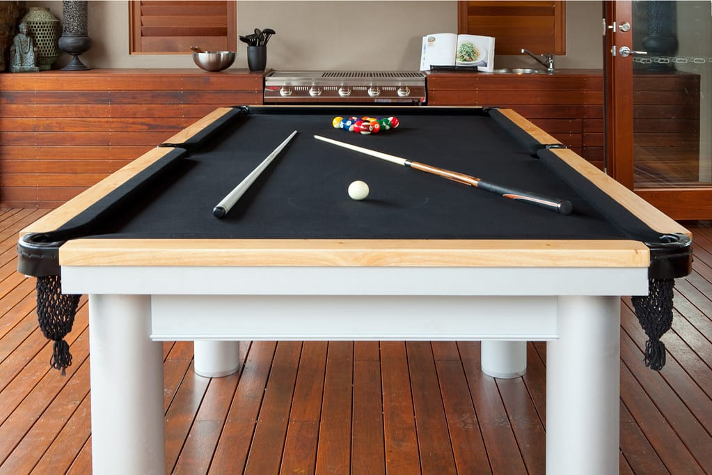 Black felt pool table on wooden deck in an outdoor area